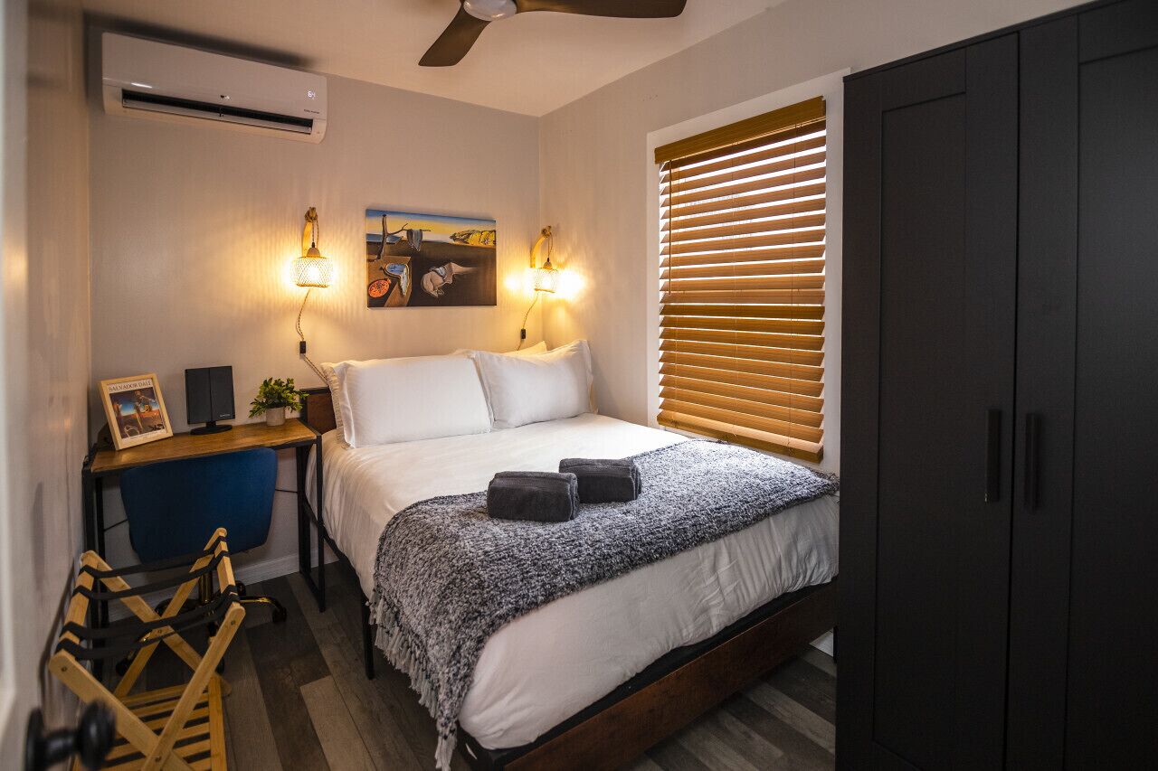 Un dormitorio con cama, mesita de noche, lámpara y armario.