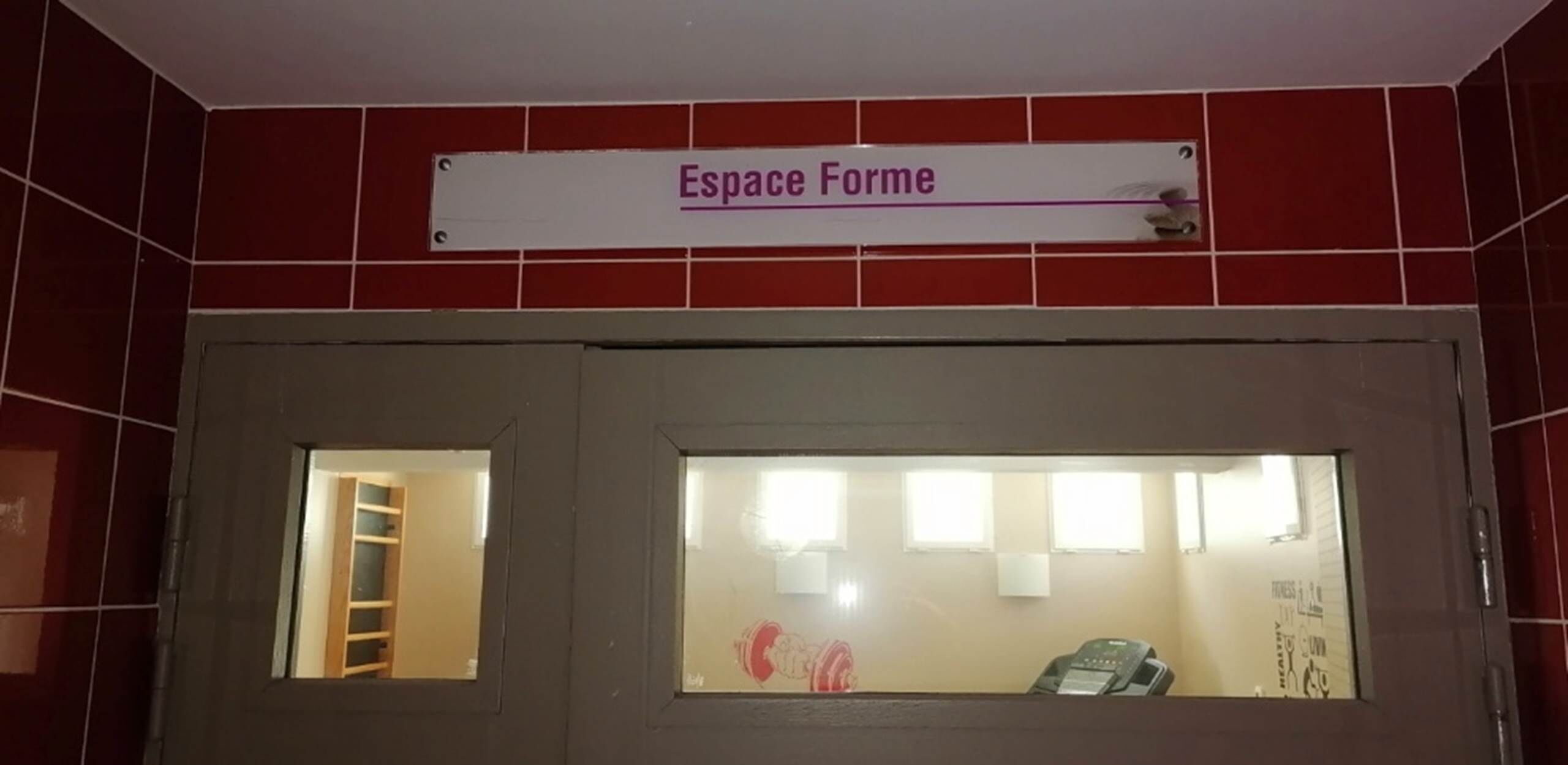 Huone, jonka oven yläpuolella on kyltti, jossa lukee ”Espace Forme”, ja ovessa on ikkuna.