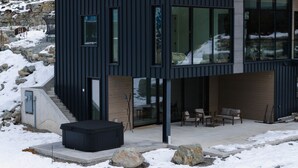 Een modern gebouw met twee verdiepingen, grote ramen, een overdekt terras en een jacuzzi.