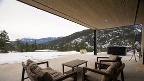 Een overdekt terras met uitzicht op besneeuwde bergen.
