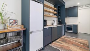 Een moderne keuken met donkere kastjes, een ingebouwde oven en een koffieapparaat.