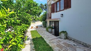 Ein zweigeschossiges Gebäude mit einem gepflasterten Weg, einem kleinen Garten und einem Balkon.