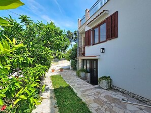 A two-story building with a stone-paved pathway, a small garden, and a balcony. - Dalero 3 by Interhome (Trogir/Okrug Gornji)