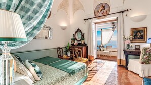 A room with a bed, a desk, a chair, a mirror, and a view of the sea. - VILLA DIOMEDEA - Villa Diomedea (Praiano)