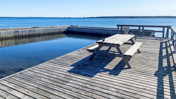 A wooden pier extending into calm water with a picnic table and benches. - Havstomten by Interhome (Blekinge)