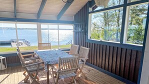 A wooden deck with a table and chairs, overlooking a body of water and a dock. - Havstomten by Interhome (Blekinge)