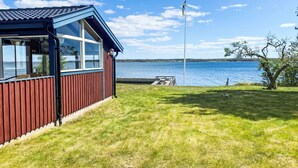 A wooden cabin with a large window overlooking a lake, a dock, and a flagpole. - Havstomten by Interhome (Blekinge)