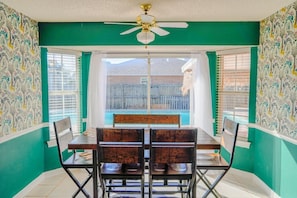 Un espace repas comprenant une table et des chaises, un ventilateur de plafond et une vue sur l’extérieur.