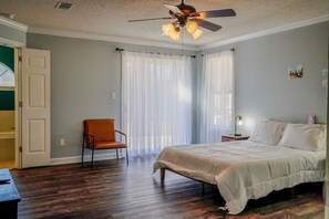 Une chambre à coucher avec un lit, une chaise, un ventilateur de plafond et une table de chevet.