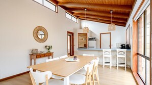 Moderni keittiö, jossa on puinen pöytä, valkoiset tuolit ja riippuvalaisin.