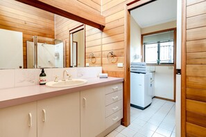 Ein modernes Badezimmer mit Holzverkleidung, einem Waschbecken mit Spiegel und einem Handtuchhalter.