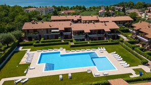 Un gran complejo turístico con varias construcciones, una piscina central y vista al mar.
