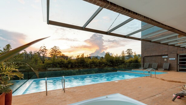 A swimming pool with a hot tub, surrounded by a brick deck and potted plants. -  Apartamentos Casa Grande (Rionegro)