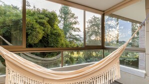 A hammock in a room with large windows overlooking a garden. -  Apartamentos Casa Grande (Rionegro)