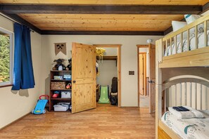 A room with a bunk bed, wooden flooring, a toy car, a green slide, and a wooden cabinet with shelves. - 4BR Mountain Escape - Covered Hot Tub, Deck, near River (Leavenworth)
