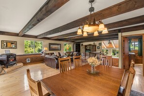 A spacious living area with a large wooden dining table, leather sofas, and a fireplace. - 4BR Mountain Escape - Covered Hot Tub, Deck, near River (Leavenworth)