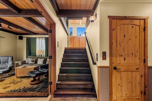 A wooden staircase leading to an upper level, a leather sofa, and a wooden door. - 4BR Mountain Escape - Covered Hot Tub, Deck, near River (Leavenworth)