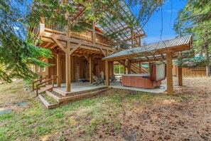 A wooden cabin with a covered porch, outdoor seating, and a hot tub. - 4BR Mountain Escape - Covered Hot Tub, Deck, near River (Leavenworth)