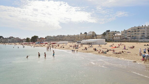 A beach with people, tents, and buildings in the background. - Port et plage à pied, linge inclus by Interhome (Le Pouliguen)
