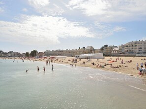 A beach with people, tents, and buildings in the background. - Port et plage à pied, linge inclus by Interhome (Le Pouliguen)
