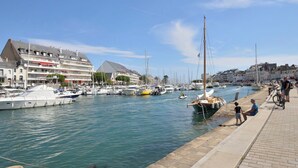 A marina with boats docked, a waterfront promenade, and buildings with balconies. - Port et plage à pied, linge inclus by Interhome (Le Pouliguen)
