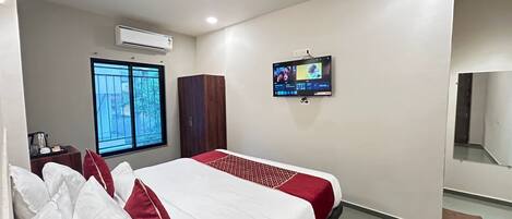 Ein Hotelzimmer mit Bett, Wandfernseher, Klimaanlage und Fenster mit Aussicht.