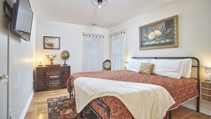 Un dormitorio con cama, cómoda, espejo, reloj, globo terráqueo y un cuadro en la pared.