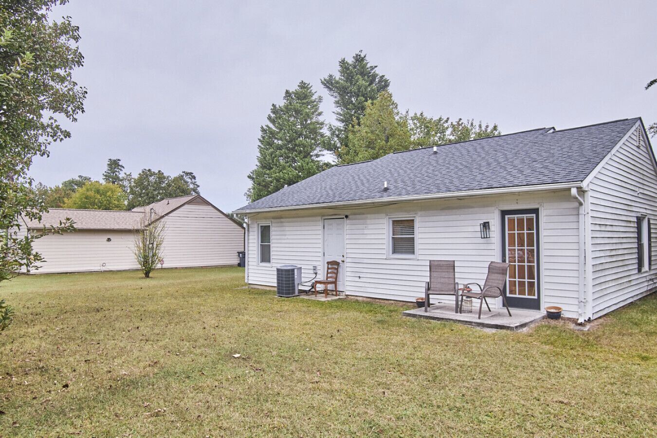 A single-story house with a front porch, a small attached garage, and a lawn.