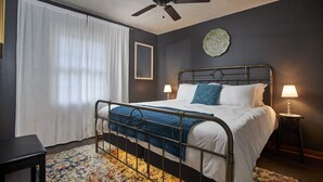A bedroom with a metal bed frame, white bedding, a ceiling fan, a bedside table with a lamp, and a floral rug. - Newly remodeled 2BR in Chapel Hill (Chapel Hill)