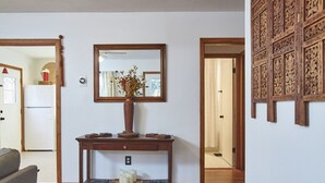 A living room with a wooden console table, a vase with dried flowers, a mirror, and a wooden panel wall. - Newly remodeled 2BR in Chapel Hill (Chapel Hill)