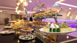 A buffet with various food items and a decorative metal stand in the foreground. - Poinciana Hotel (Makkah)