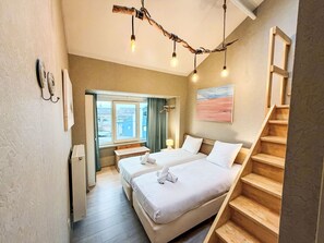 A hotel room with two beds, a wooden staircase, a window with a view, and a painting on the wall. - Tureluur II with terrace by Interhome (Bredene)