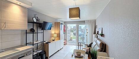 Una cocina moderna con comedor, televisor y bicicleta.