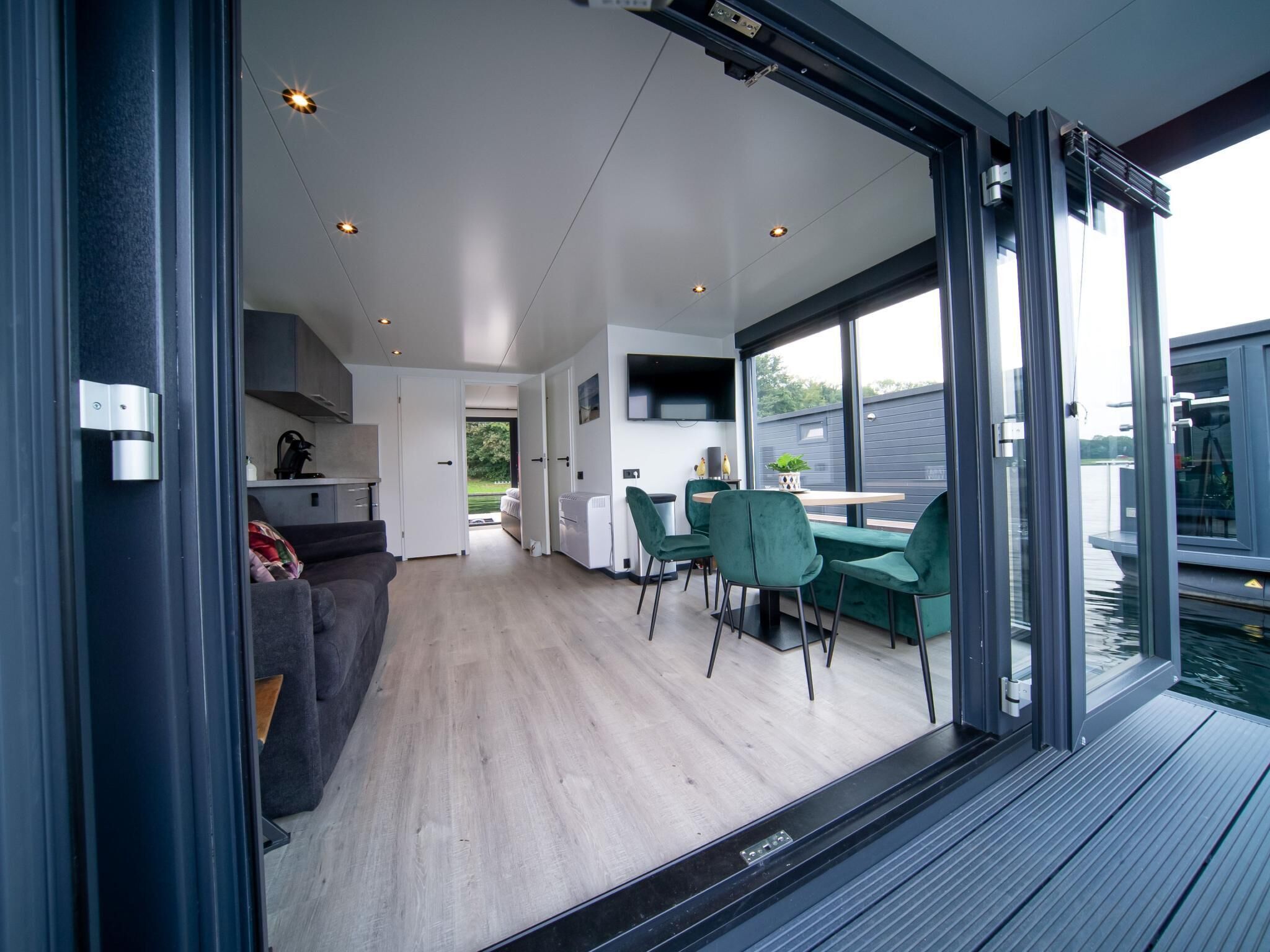A modern interior with a dining area, kitchen, and a view of the water.