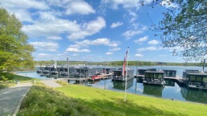A marina with several docked boats, a flagpole with a flag, and a grassy area with a pathway.