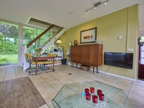 A modern living room with a staircase, a dining area, and a TV mounted on the wall. - Wellness and tranquillity in green Twente (Oldenzaal)