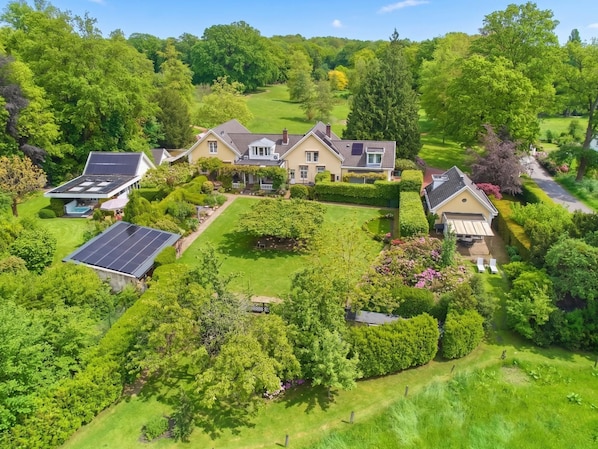 Ein großes, modernes Haus mit mehreren Solaranlagen, umgeben von üppiger Vegetation und einem gepflegten Rasen.