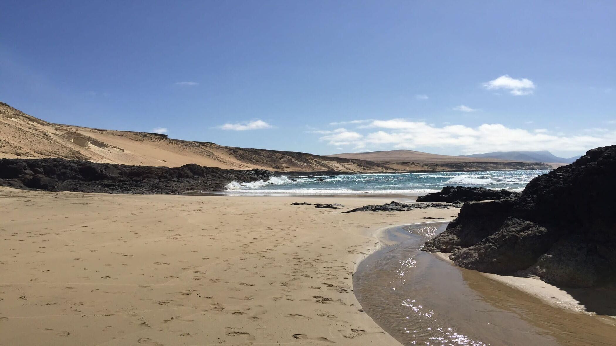 A beach with a rocky shoreline, sandy beach, and ocean waves.