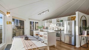 Une cuisine moderne avec des meubles blancs, des appareils en acier inoxydable et un îlot central.