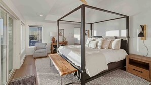 Une chambre moderne avec un lit à baldaquin, un ventilateur de plafond, un banc et une vue sur l’extérieur.