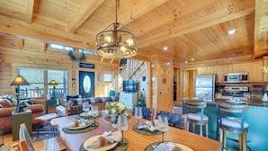 A spacious wooden cabin with a dining area, kitchen, and living room. - Resort-Style Smokies Cabin w/ Hot Tub + Game Room (Pigeon Forge)