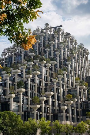 Un edificio moderno con un diseño arquitectónico único, con varios balcones sobresalientes adornados con plantas.