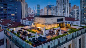 Eine Dachterrasse mit Außenmöbeln, einer Bar und Blick auf die Skyline der Stadt.