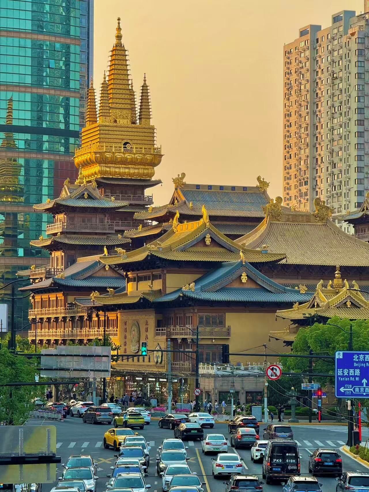 A traditional Chinese building with ornate golden roofs and multiple tiers, surrounded by modern high-rise buildings and busy traffic.