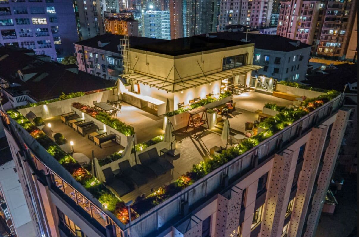 A rooftop terrace with outdoor seating and a pool area, surrounded by high-rise buildings.