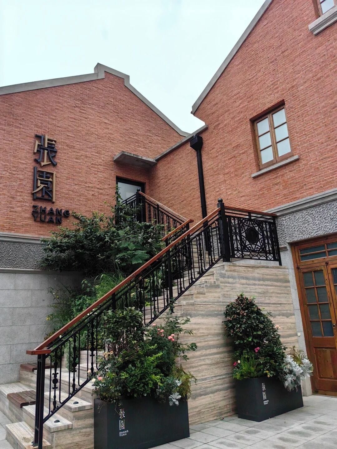 Una escalera conduce a un edificio de ladrillo con un letrero que dice "ZHANG YUAN".