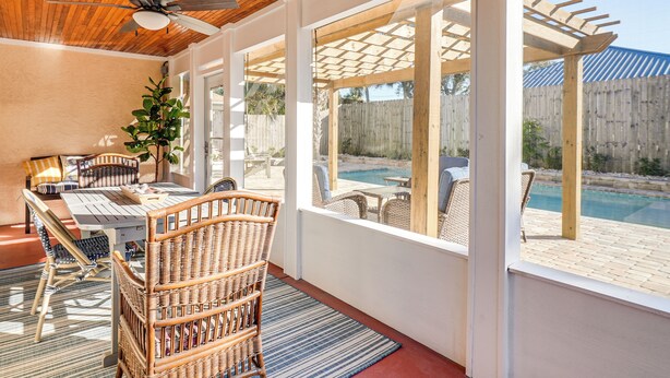 Un patio techado con una mesa de comedor, sillas de mimbre y un ventilador de techo.
