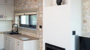 Cozinha moderna com paredes de pedra, forno embutido e televisão de tela plana.