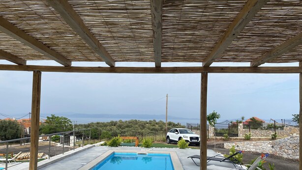 Piscina descoberta coberta com vista para um carro branco e paisagem distante.