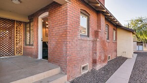 Ein Backsteinhaus mit überdachter Veranda, einem kleinen Fenster und einer Tür.